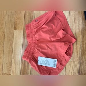 LULULEMON TRACKER LR SHORTS 4’ LINED, WMCO (sunset orange color)